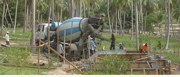 Thai construction workers on building site under palm trees